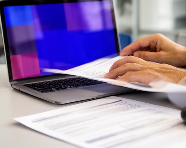 Unternehmerin prüft Vertragsunterlagen mit Laptop in einem modernen Büro